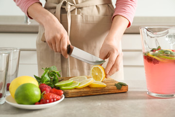 Woman preparing fresh lemonade on table