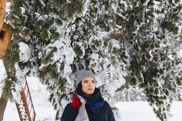 Portrait of a girl standing under a snow-covered pine