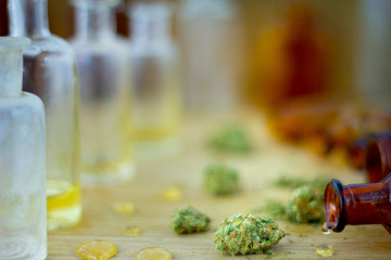 Medical Oil of Cannabis -  view of marijuana oil, leaking resin from old antique apothecary jar and marijuana flowers on fresh oak wood background.