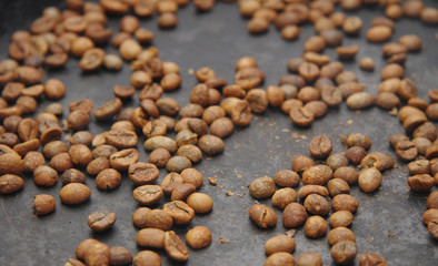 Green coffee beans roasting on the black pan