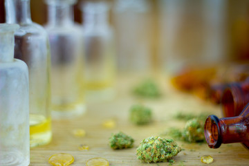 Medical Oil of Cannabis -  view of marijuana oil, leaking resin from old antique apothecary jar and marijuana flowers on fresh oak wood background.