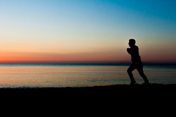 Fototapeta premium Silhouette of runner old man in the morning at the beach, sunrise Background.