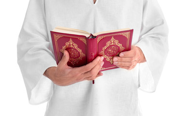 Young Muslim man reading Koran on white background