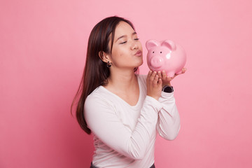 Young Asian woman kiss  a pink coin bank.