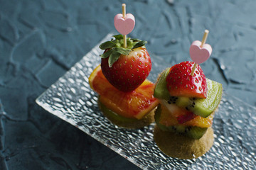 two canapés with strawberry, kiwi, orange on the glass plate