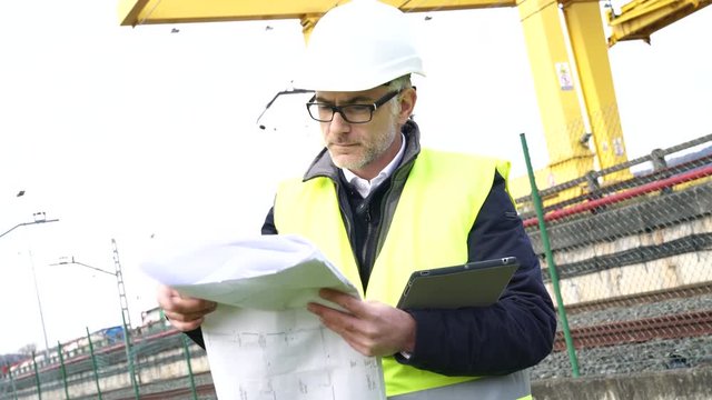 Construction manager on site reading blueprint