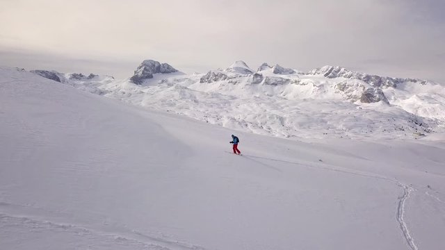Young man climbing on ski in Alps, aerial footage of winter activity. 