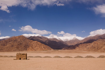 Scenic landscape with buddhist ruins in highland desert with snow mountains background. Himalayas. Region Ladakh. State Jammu and Kashmir. India.