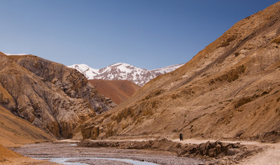 Bike trip through winding road along the river on himalaya highlands. Lonely biker driving in canyon. Region Ladakh. India. State Jammu and Kashmir.