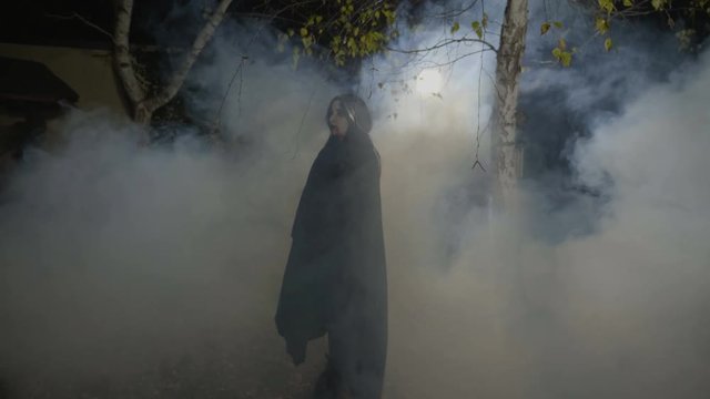 Zombie female vampire smiling maleficent and walking among trees on halloween moonlight