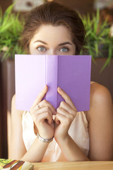 Young brunette caucasian woman at the cafe in european city study, reading book and working on her devices. Summer sunny weather. She in red skirt and romantic blouse, smile happily. Copy space