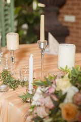 Wedding table decor full of rose and eustoma flowers, candles and peach colored fabric. Luxury rich restaurant interior. Indoor. Copy space