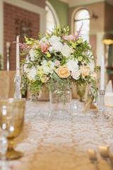 Wedding table decor full of rose and eustoma flowers, candles and peach colored fabric. Luxury rich restaurant interior. Indoor. Copy space