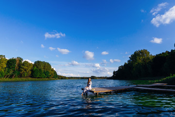 Fototapeta na wymiar woman sitting on the pier of the lake in beautiful sunny day on