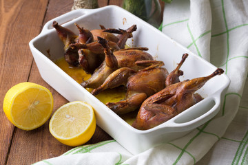 Appetizing baked quail with spices, herbs and lemon, lime in white form for baking on a wooden table