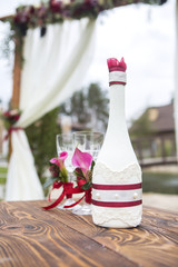 Set of wedding glassess with wine color flowers and ribbon on a wooden surface (table). Outdoors. Copy space
