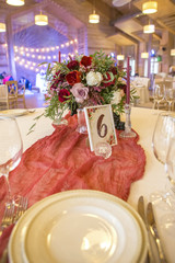 Set of wine flowers on a wedding table surrounded by plates, tablecloths and candles. Interior. Copy space