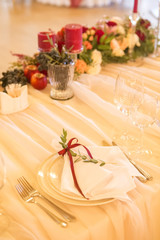 Set of glassess and plates on a wedding table surrounded by light garland and wine color flowers and tablecloth. Interior. Copy space