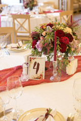 Set of wine flowers on a wedding table surrounded by plates, tablecloths and candles. Interior. Copy space