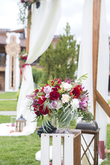 Wine color flowers on a wedding arch with tulle fabric and wooden decorations. Copy space