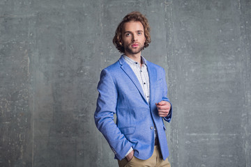 Portrait of pensive unshaven young businessman having dream while putting hand in pocket