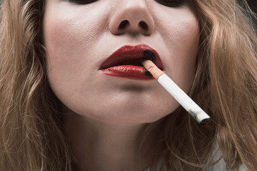 Obraz premium Close up of female mouth holding cigarette, black spots are on red lips