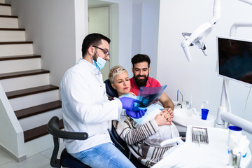 Attractive bearded man with his pregnant wife having medical treatment in dental office