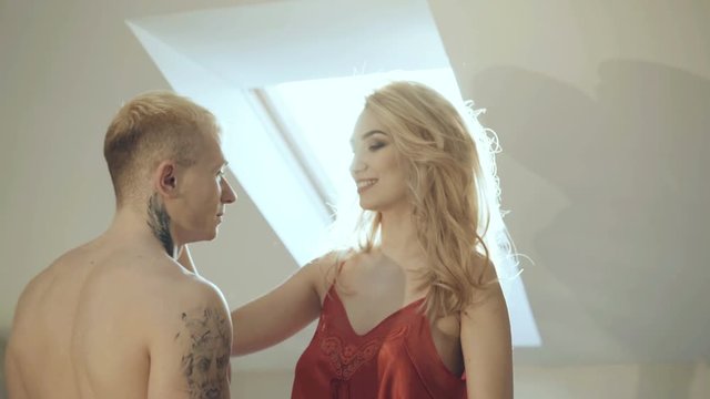 Seductive blonde in red nighty caresses and kisses with brutal man