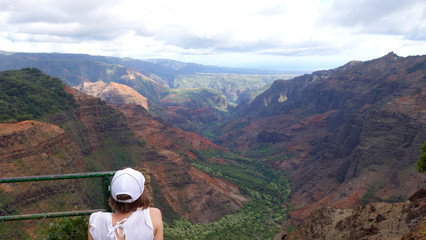 Fototapeta na wymiar Curious girl is looking at Waimea Canyon in Kauai (HI, USA)