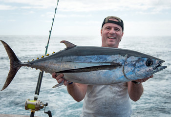 Happy angler holding big tuna fish - 194773757