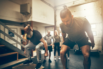 Fototapeta na wymiar Two men doing box jumps during a gym workout session