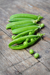 Pods of green peas on a wooden background
