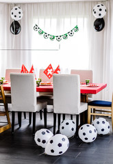 Kids birthday party Football theme. Table decorated in red and green colours with balloons in black and white.