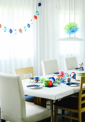 Multi-coloured kids birthday party Rainbow themed. Decorated table with hanging paper lights.