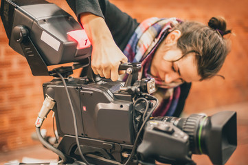 Obraz premium Behind the scene. Female cameraman shooting film scene with camera