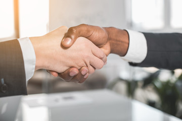 Successful finalize agreement. Two guys are shaking hands in office. Close up