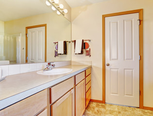Warm beige bathroom with light wood cabinets.