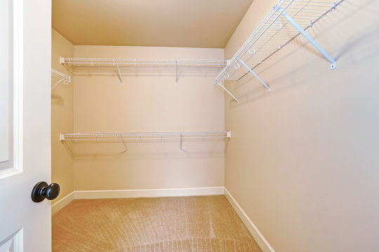 Empty Walk In Closet With Shelves And Carpet Floor.