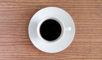 A cup of hot white coffee is placed on a desk in the office with a drink in the morning.