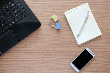 Flat lay, top view office table desk. Workspace with smartphone, laptop, binder clips of colour., mint diary on wooden background.