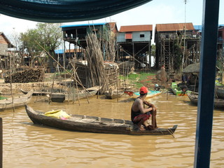 Man, boat, river and houses, Kampong Khleang, Cambodia