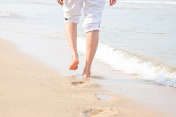 Fototapeta na wymiar Legs of young women walking on the beach.