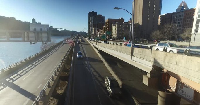 A dolly-up reveal of the Pittsburgh city skyline and street traffic on a late winter sunny day.  	