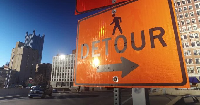 An establishing shot of an orange detour sign in downtown Pittsburgh, Pennsylvania.  	