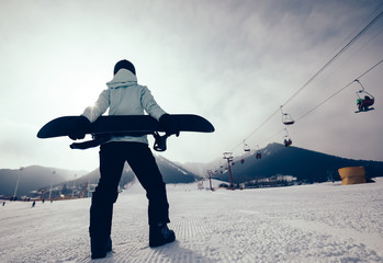 snowboarder with snowboard on ski piste in winter mountains