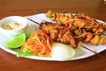 Delicious Chicken Tikka and Vegetable tikka with yogurt dipping served in white plate. Chicken dish.