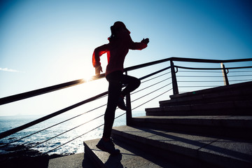 sporty fitness female runner running upstairs on coast trail