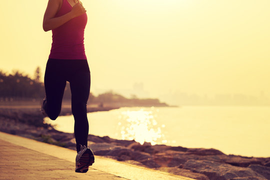 sporty fitness woman running on sunrise seaside trail