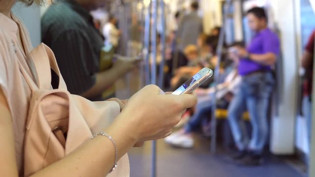 Closeup Of Female Commuter Hands Using Smartphone In Tube