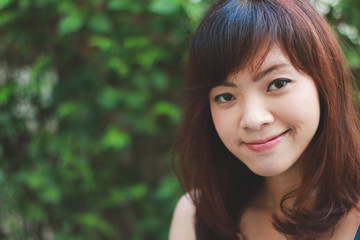 Fototapeta premium Close up of young pretty Asian woman in blue dress with garden background.